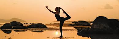 A woman is doing yoga on the beach