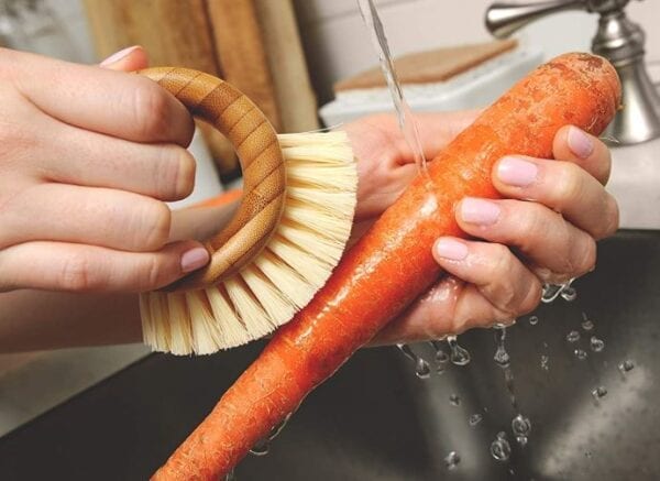 scrubbing carrot with wooden scrubber